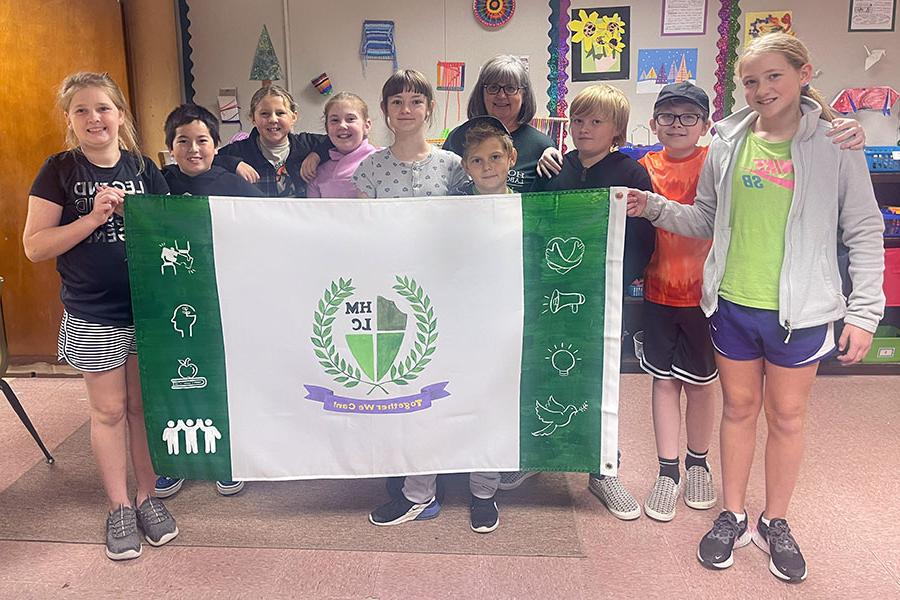 Horace Mann students in Sarah Winters’ fifth and sixth grade classroom, 与美术老师洛里·阿特金斯合影, 设计了一面代表他们学校的旗帜. (提交的图)